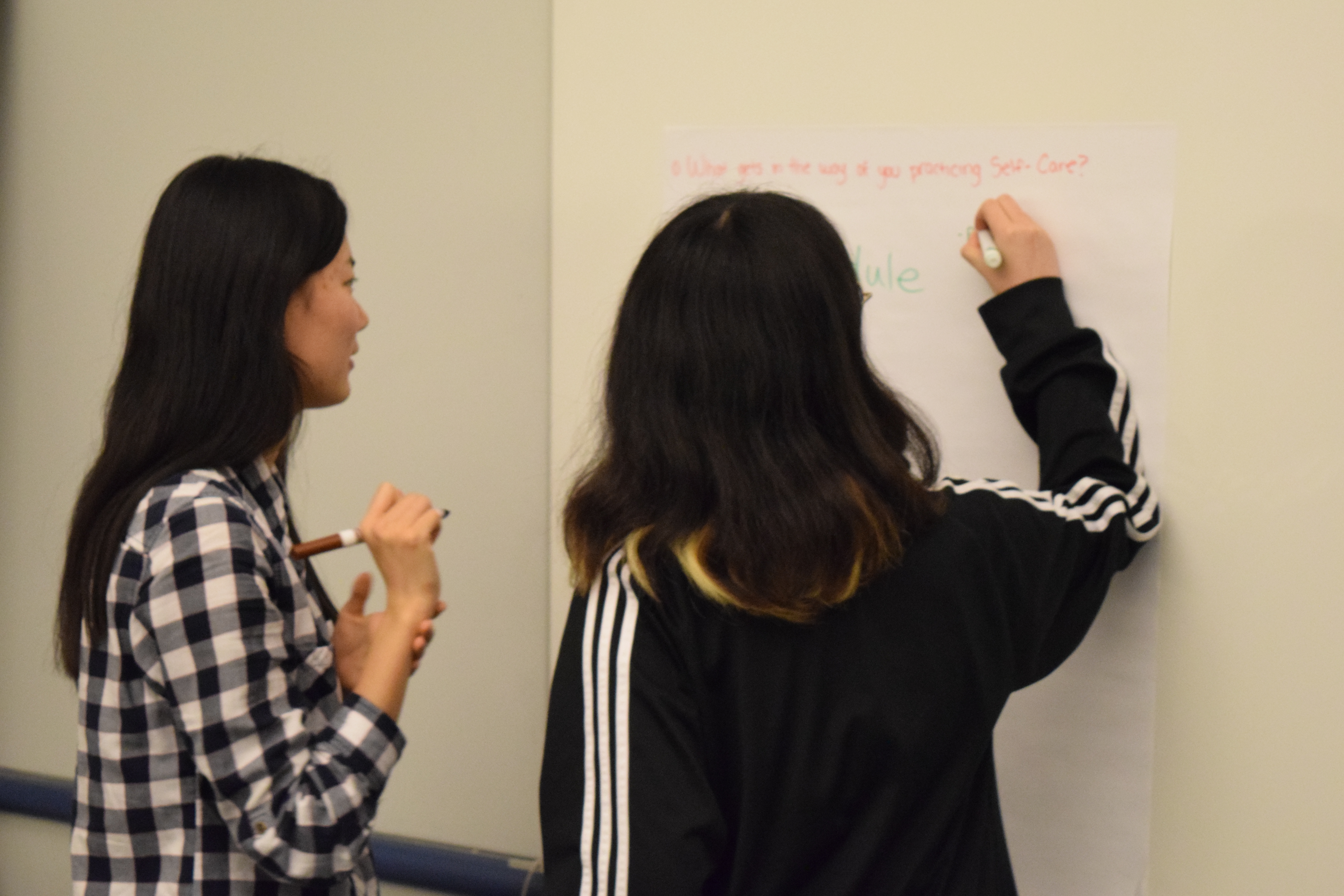 Workshop students write on large post it note for activity 