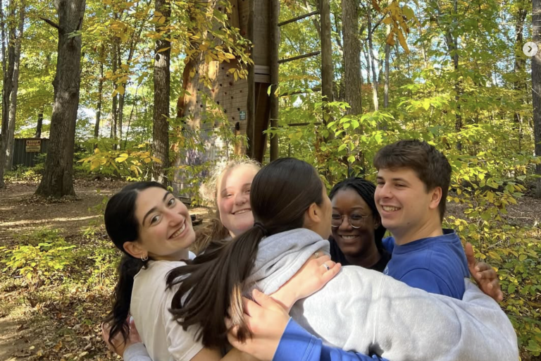 Student Group smiles for the camera while working on problem solving at the challenge course