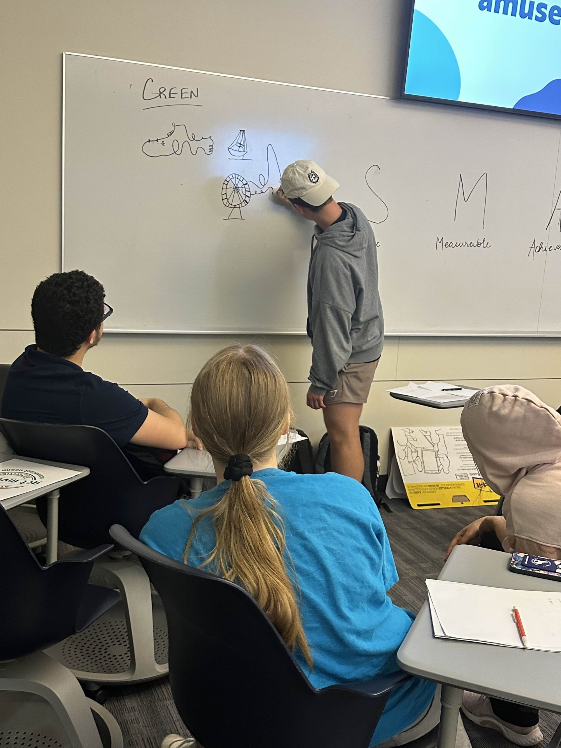 Student writing on whiteboard for activity